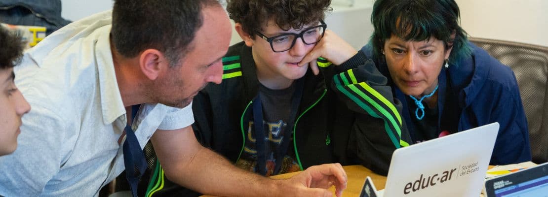 Dos docentes junto a un alumno frente a una computadora